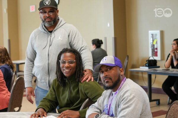 689300379_18226207318314357_440400015276587959_n-600x400 | Akron Urban League Three Adults Pose at a Community Event: a Man in a Gray Hoodie and Cap Stands Behind Two Seated Friends (woman in Green, Man in Purple Cap).