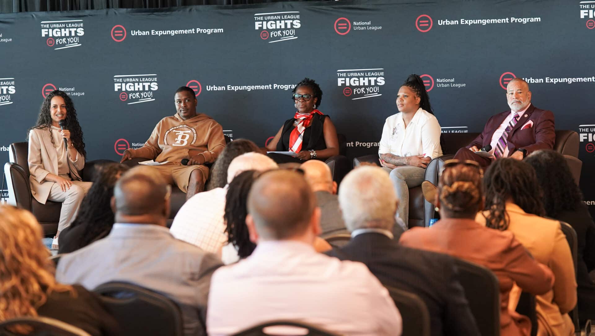 Barrier Removal | Akron Urban League Panel Discussion with Five Speakers on a Stage in Front of an Urban League Backdrop Reading 'fights for You' and 'urban Expungement Program' with an Audience in Foreground