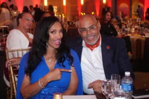 Dsc05487-300x200 | Akron Urban League Smiling Couple at a Formal Dinner; Woman in a Blue Dress Points to the Man Beside Her.