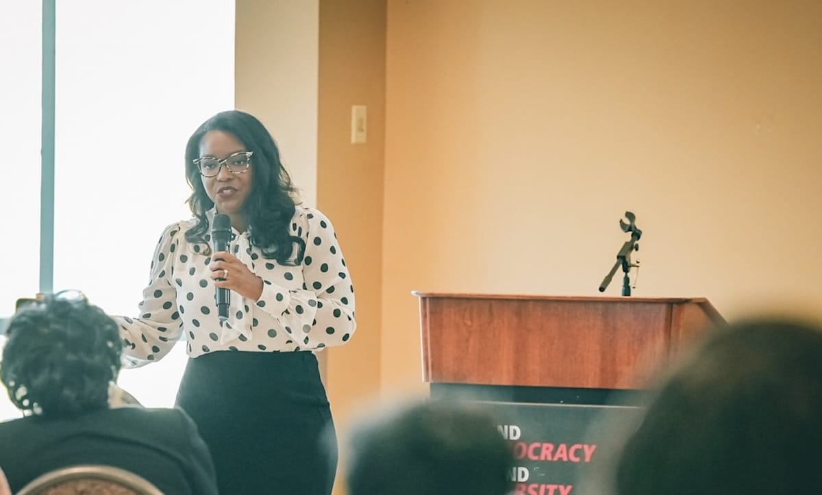 Entrepreneur Empowerment Center Hero | Akron Urban League Group of Black Women and Men at a Political Advocacy Rally. a Woman Speaks into Microphones at a Podium.