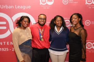 Img_0740-300x200 | Akron Urban League Four People Posing for a Group Photo at an Urban League Event, with a Pink Backdrop and Logos Behind Them.