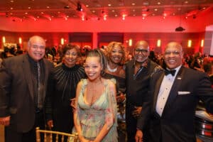 Img_2215-300x200 | Akron Urban League Group of Seven Adults in Formal Attire Posing and Smiling at a Gala Event, with Red Lighting in the Background.