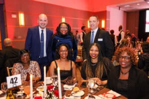 Img_2228-300x200 | Akron Urban League Group of Six Adults at a Formal Dinner, Seated Around a Round Table with Candles and Red Decor, Smiling for the Camera at a Banquet Venue Cream Walls.