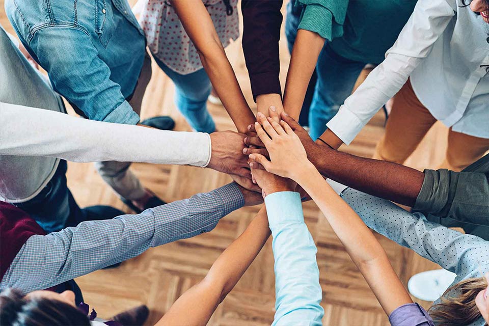 Diverse group of people all putting their hands together