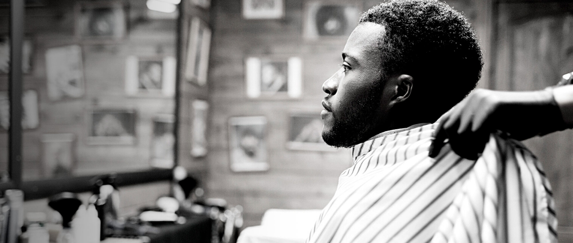 Young Black man getting fitted with gown at the barber