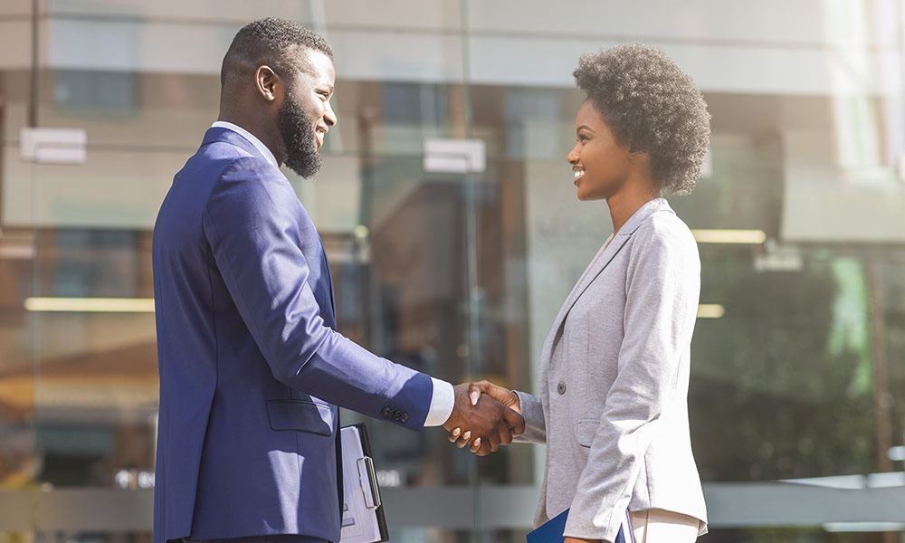 Young Black business people shaking hands outdoors