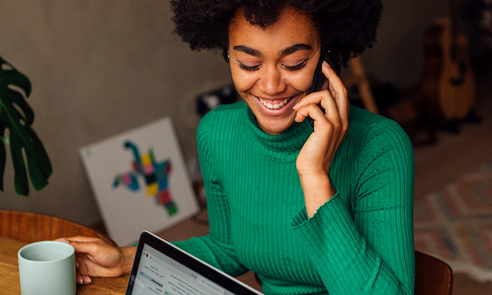 Young Black woman drinking coffee talking on the phone